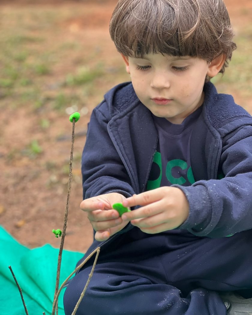 Criança da Educação Infantil do COC Pinhal modelando massinha ao ar livre
